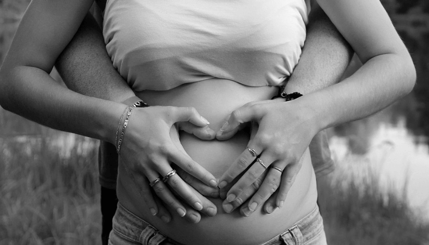 mulher gravida fazendo coração com as mãos na barriga