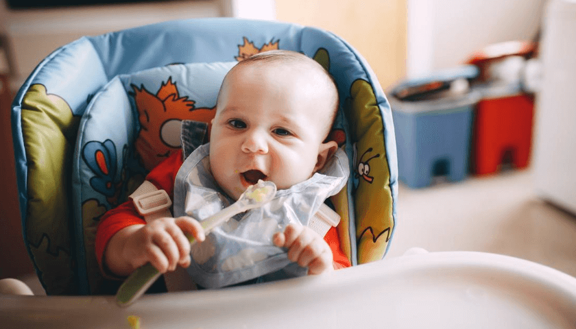 bebê menino com babador comendo papinha