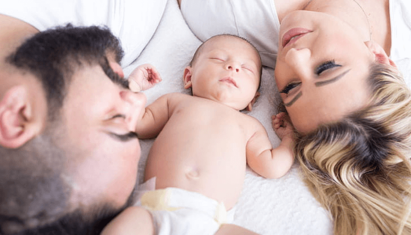 bebe de fralda com a mamãe e papai na cama