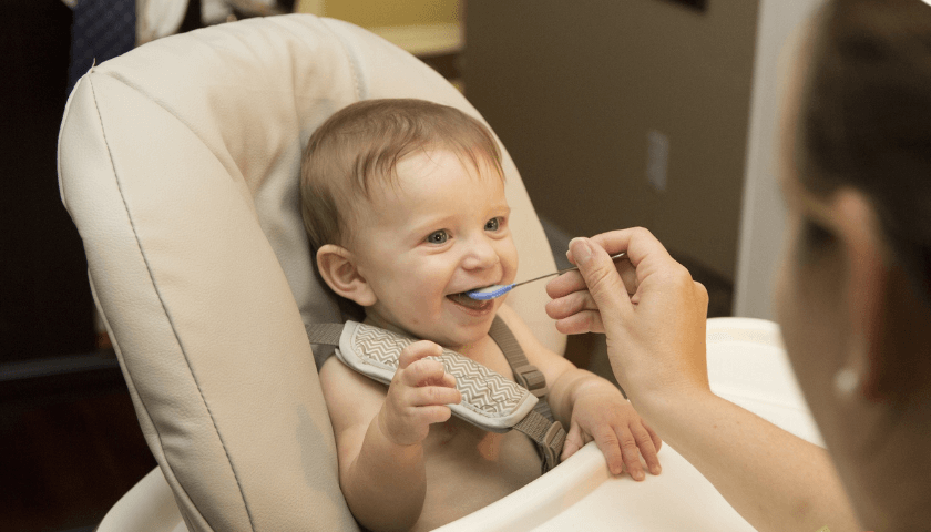 bebê menino com babador comendo papinha