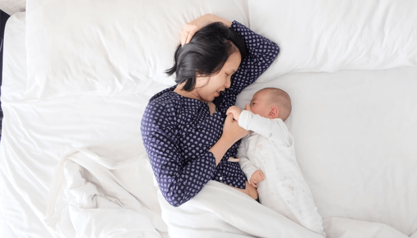 mãe amamentando o bebê na cama